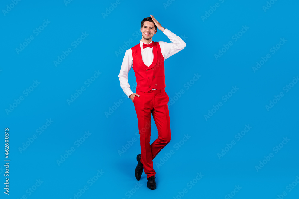 Full size photo of young man happy positive smile hand touch hair new hairdo barber shop isolated over blue color background Full size photo of young man happy positive smile hand touch hair new hairdo barber shop isolated over blue color background