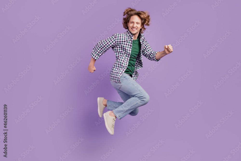 Full body profile side photo of young man good mood jump runner wear casual outfit isolated over violet color background Full body profile side photo of young man good mood jump runner wear casual outfit isolated over violet color background