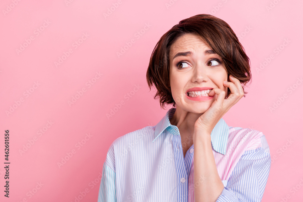 Photo of young woman bite fingers teeth worried scared nervous fail look empty space isolated over pink color background Photo of young woman bite fingers teeth worried scared nervous fail look empty space isolated over pink color background