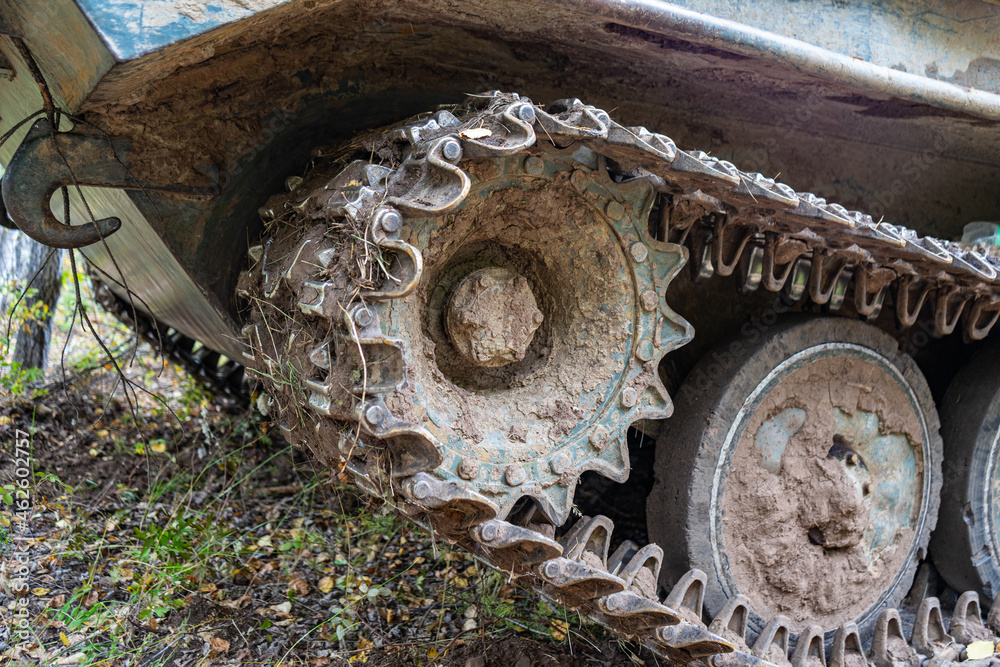 Chassis of tracked military equipment. Metal tracks of a tracked vehicle in dried mud. Cogwheel of a combat vehicle Chassis of tracked military equipment. Metal tracks of a tracked vehicle in dried mud. Cogwheel of a combat vehicle