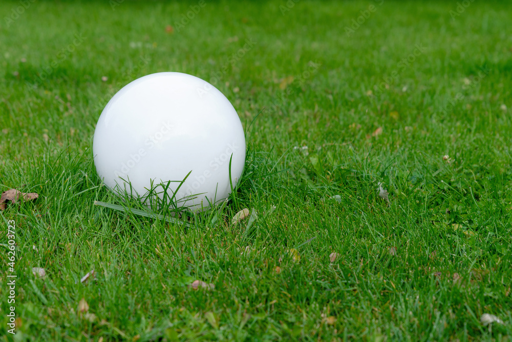 Lighting ground street lamp in the shape of a ball mounted on a green lawn in the park. Street round white lanterns. Copy space for you text. Lighting ground street lamp in the shape of a ball mounted on a green lawn in the park. Street round white lanterns. Copy space for you text.