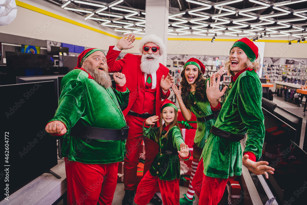 Photo of funky excited santa claus assistants wear costumes smiling buying tv-sets indoors shopping center