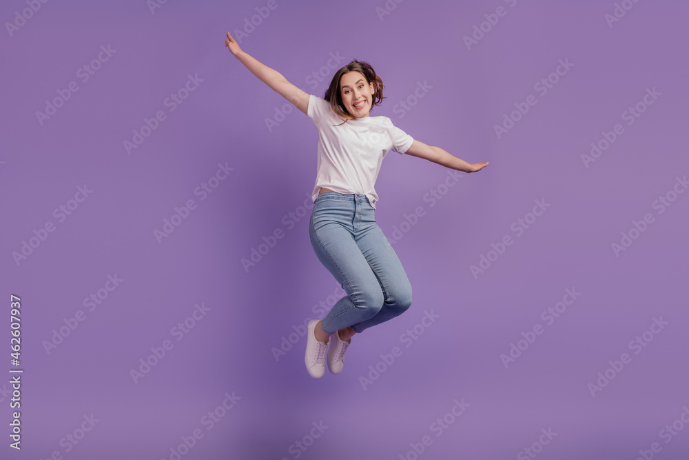 Fototapeta premium Full size photo of young cheerful girl jump up hands wings casual outfit isolated on violet color background