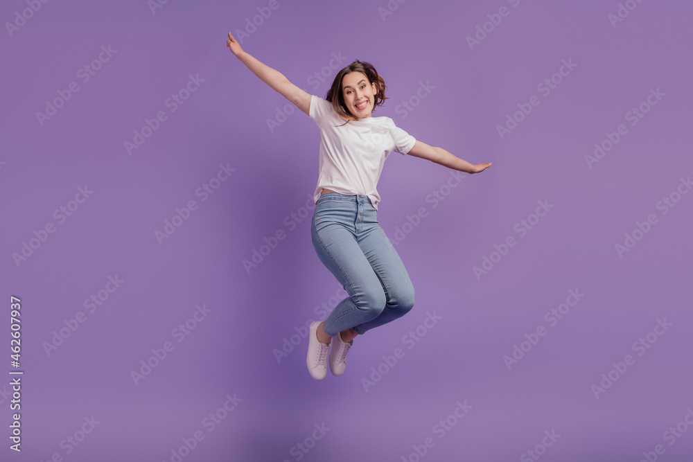 Full size photo of young cheerful girl jump up hands wings casual outfit isolated on violet color background