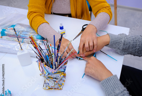 Therapist hands helping person with special needs make handmade souvenir using glue and paper photo