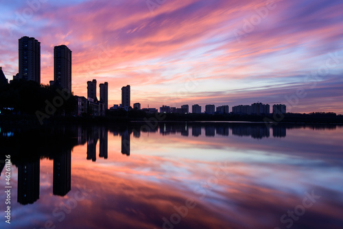 The river in the city Park reflects the city skyline against a beautiful and spectacular sunset backdrop. © Xiangli