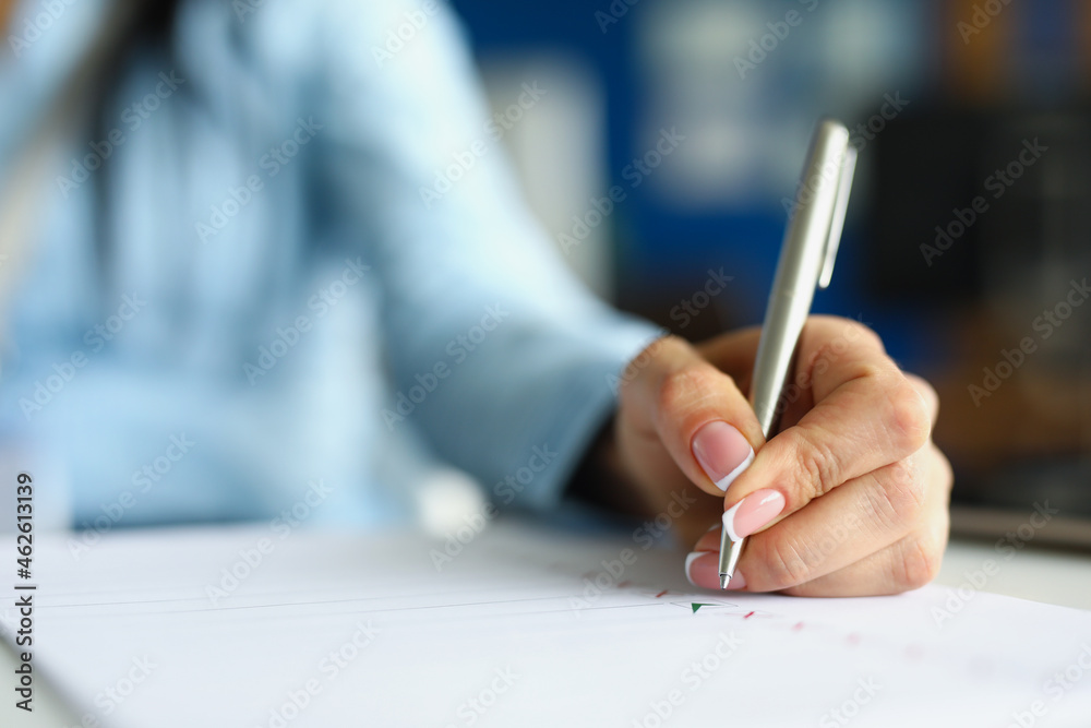 Woman hand writing with silver ballpoint pen in notebook closeup Woman hand writing with silver ballpoint pen in notebook closeup