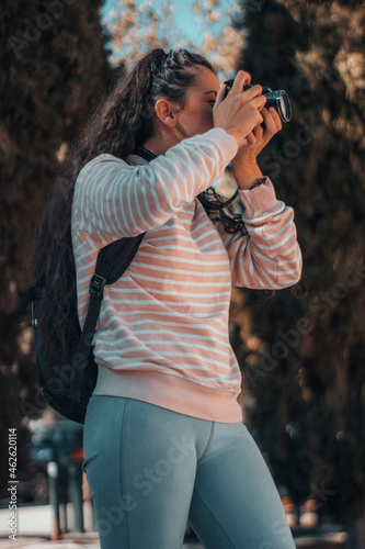 Mujer joven profesional fotógrafa haciendo fotos de turista en el exterior junto con su mochila y equipaje para terminar su sesión de fotos de su viaje