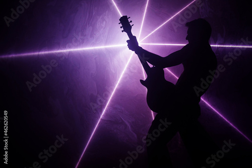 Mężczyzna z gitarą na tle światła laserowego