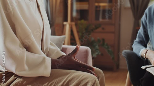 Close up shot of Caucasian psychologist putting hand on hand of African American woman while comforting patient during therapy session photo