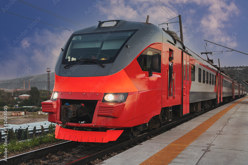 A red passenger train arrives at the railway station. Intercity communication.