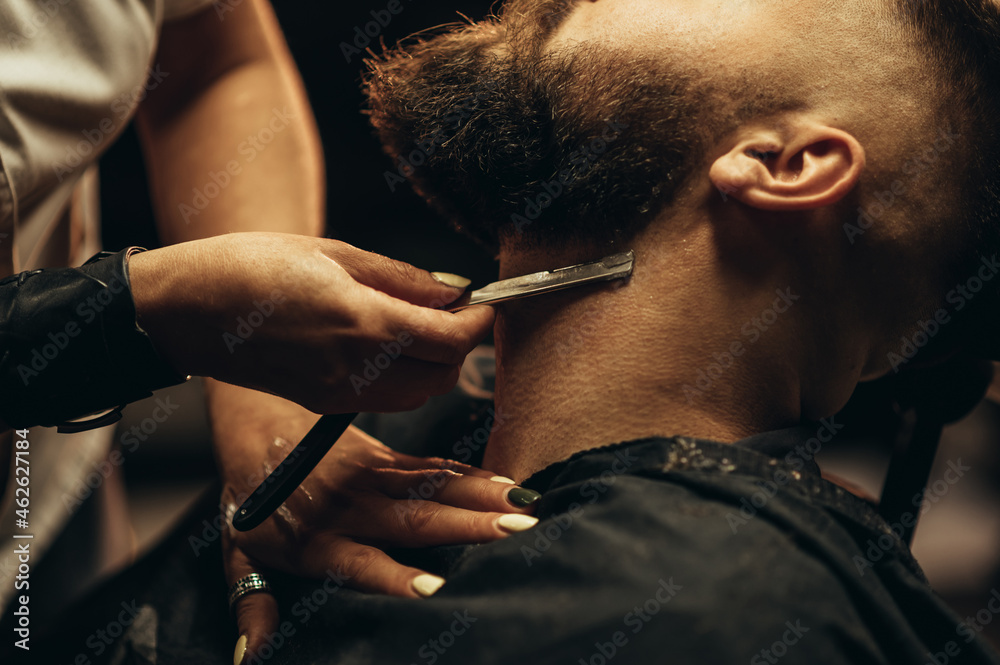 Φωτογραφία Man getting shaved with straight edge razor by hairdresser at barbershop