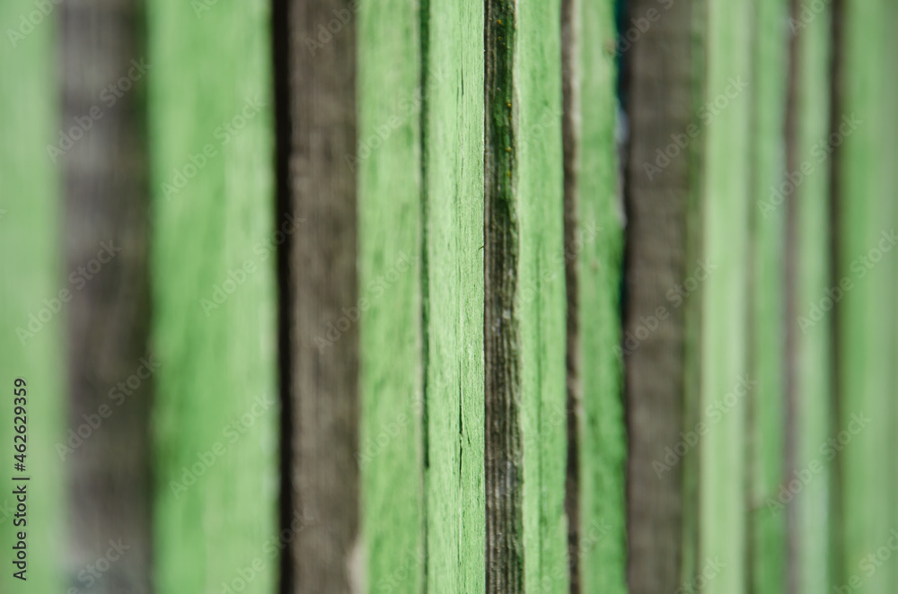 Fototapeta premium Close-up old green wooden fence with copy space. Wall of frayed wooden planks. Texture of old wooden planks with peeling paint. Background and texture for design.