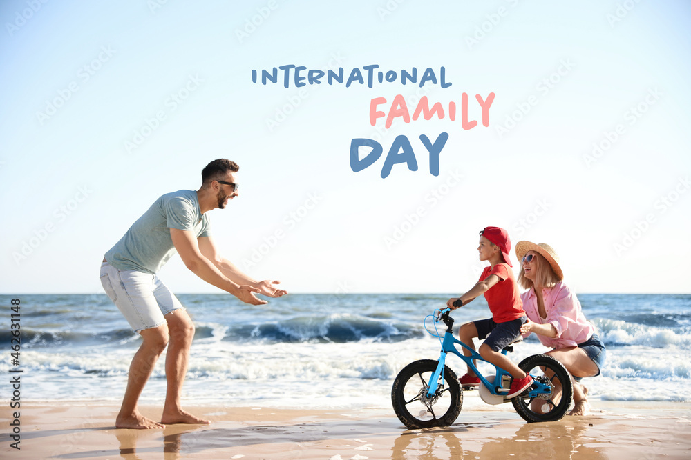 Fototapeta premium Happy parents teaching son to ride bicycle on sandy beach near sea. Happy Family Day