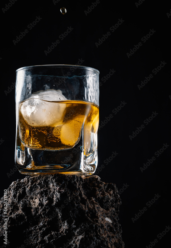 Glass of refreshing whiskey in black studio Glass of refreshing whiskey in black studio