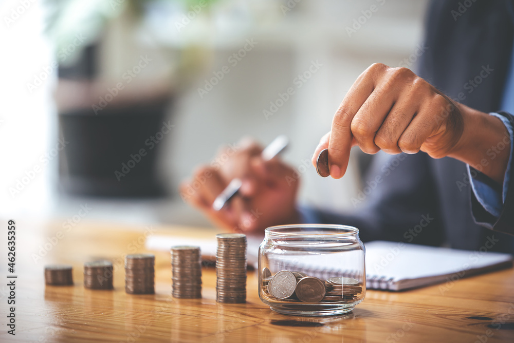 businessman holding a coin in a glass On a table with sunlight. Money Saving Ideas for Financial Accounting