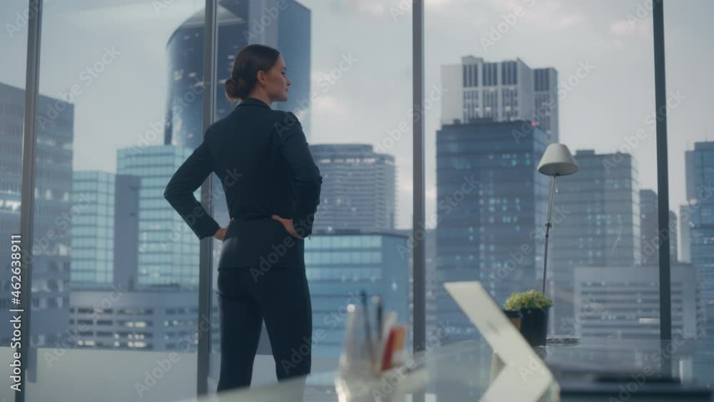 Successful Businesswoman in Stylish Suit Looking out of the Window at Big City in Downtown Area. Confident Female CEO Working on Financial Projects. Real Estate Agent Planning a Development Deal. Successful Businesswoman in Stylish Suit Looking out of the Window at Big City in Downtown Area. Confident Female CEO Working on Financial Projects. Real Estate Agent Planning a Development Deal.