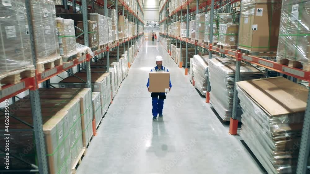 Storehouse worker is carrying a heavy box through the premises Storehouse worker is carrying a heavy box through the premises