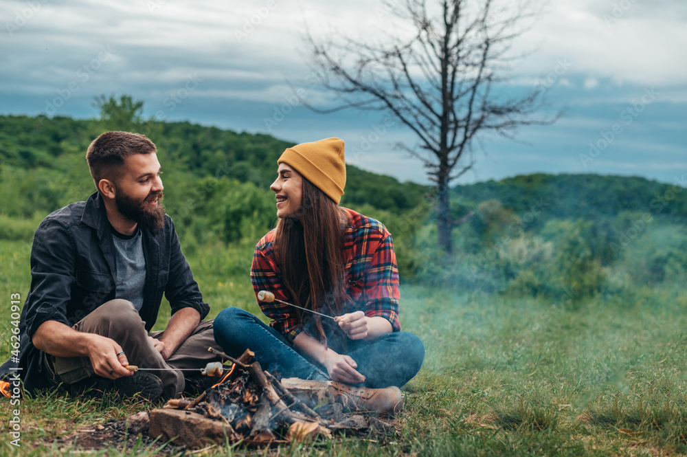 Couple of campers eating marshmallows while camping in the nature