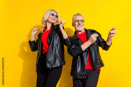 Portrait of beautiful handsome pensioner cheery grey-haired friends resting dancing isolated over shine yellow color background