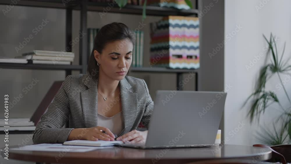 Business woman writing something in notebook. Start-up woman entrepreneur student studying writing note at workplace near computer. A womans hand writing down on a white blank notebook on table. Business woman writing something in notebook. Start-up woman entrepreneur student studying writing note at workplace near computer. A womans hand writing down on a white blank notebook on table.