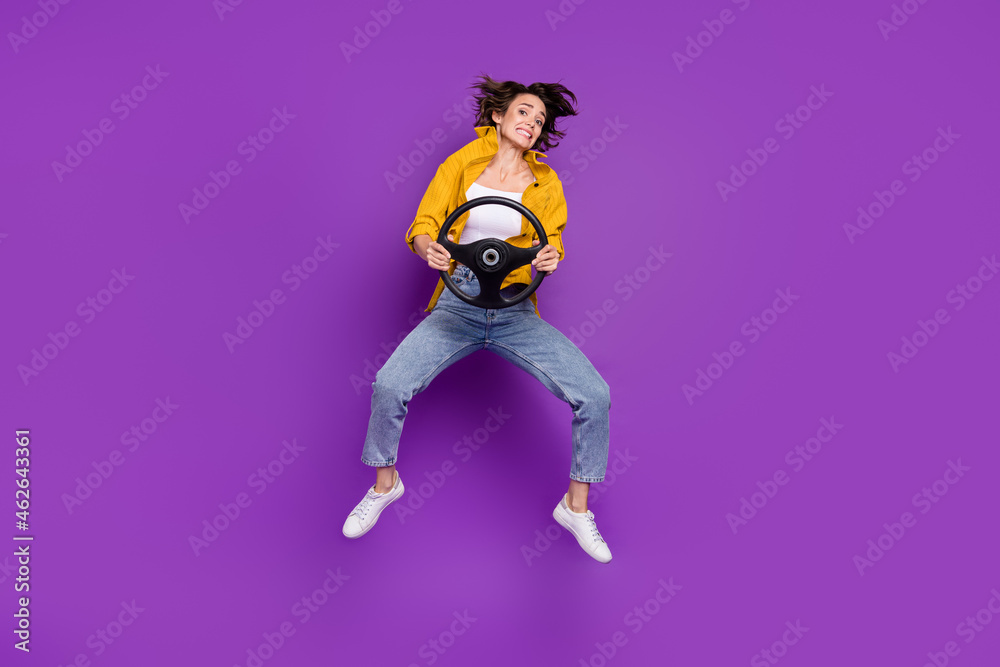 Full length body size view of attractive puzzled girl jumping holding steering wheel isolated over bright violet purple color background