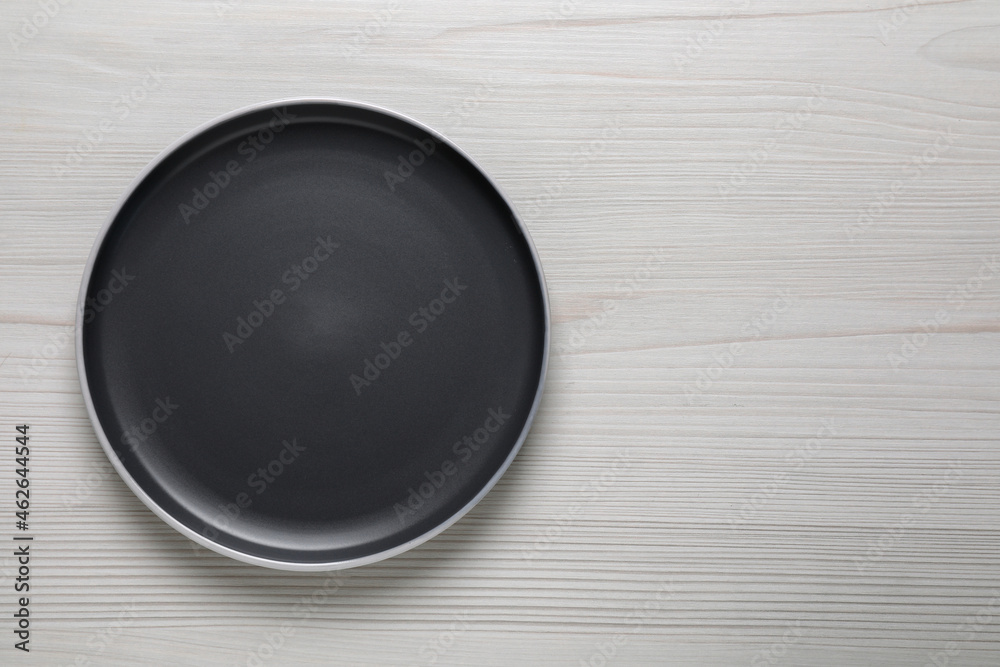 New dark plate on white wooden table, top view. Space for text New dark plate on white wooden table, top view. Space for text