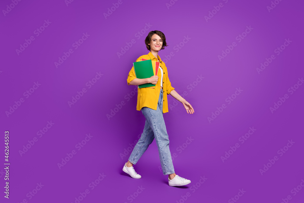 Full length body size view of attractive cheery girl holding materials going college isolated over bright violet purple color background Full length body size view of attractive cheery girl holding materials going college isolated over bright violet purple color background