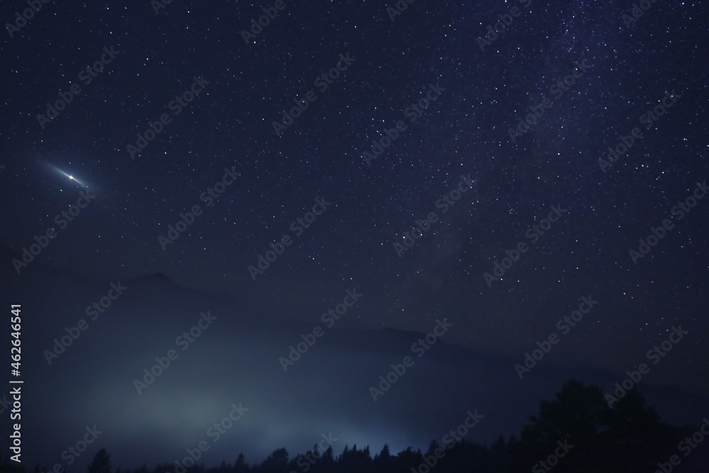Picturesque view of night sky with beautiful stars over foggy hill