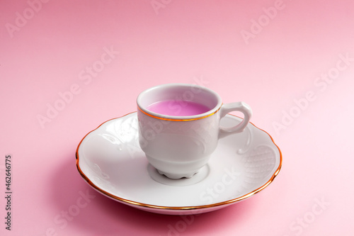 Close-up of coffee cup and plate with rose coffee or tea. Pink background. Minimalism