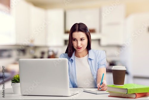 A happy focused female adult student with a laptop attending the online lesson,