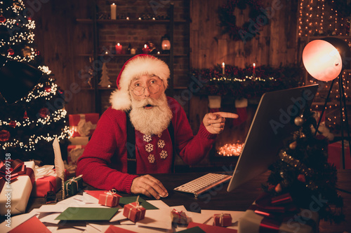 Photo of aged santa claus amazed shock point finger computer wow christmas holiday decor miracle indoors