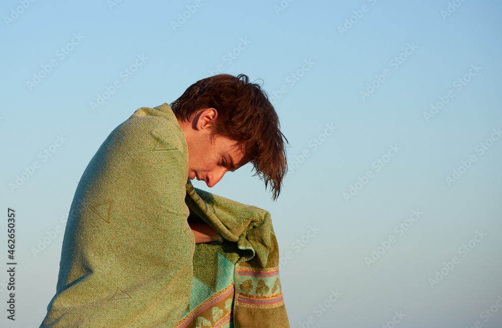 A man on the beach drying himself with the towel