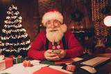 Photo of influencer santa claus sit workspace hold telephone blog post wear hat sweater in north pole office indoors