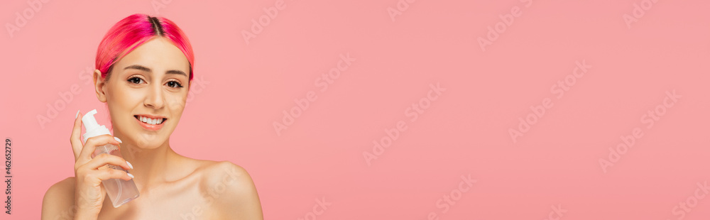 happy young woman with colorful hair holding bottle with toner isolated on pink, banner happy young woman with colorful hair holding bottle with toner isolated on pink, banner