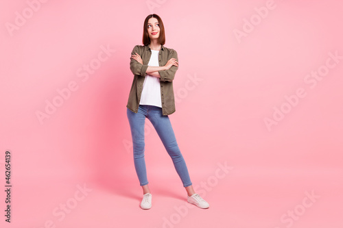 Full size photo of cute brunette hairdo millennial lady crossed arms look empty space wear green shirt jeans isolated on pink color background