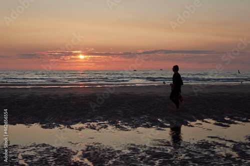 A rear view of a lady walking at the beach enjoying the scenic sunset