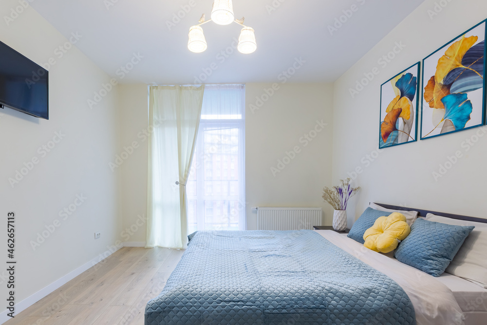 Interior of a small bedroom in a modern minimalist style, in light colors, a large bed with a blue blanket Interior of a small bedroom in a modern minimalist style, in light colors, a large bed with a blue blanket
