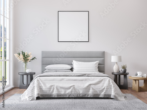 Empty square frame for print or poster mockup on white wall in modern neutral gray bedroom interior with wood floor, rug with geometric pattern, bedside tables, lamps, decor and plants. photo