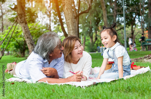 Grandfather and grandmother playing on the green grass with grandchildren in the park, Holiday with grandparents, Summer with grandparents, Concept family vacation lifestyle, Green nature background © amorn