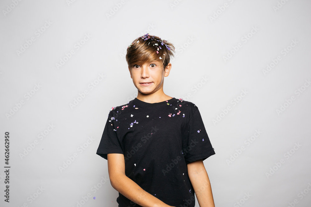 Portrait of a twelve years old boy throwing confetti to the air Portrait of a twelve years old boy throwing confetti to the air
