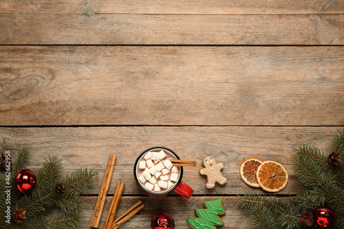 Flat lay composition of delicious hot chocolate with marshmallows and Christmas decor on wooden table, space for text