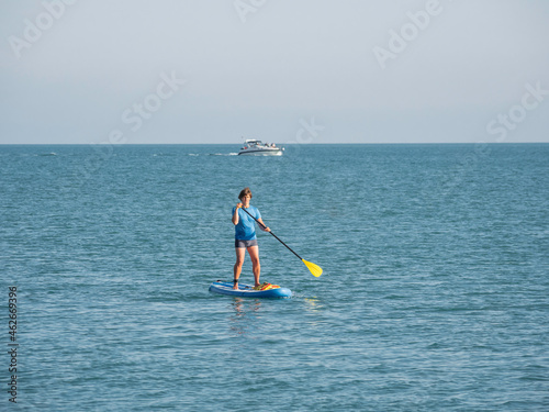 Paddle boarder. Sportsman paddling on stand up paddleboard. SUP surfing. Active lifestyle. Outdoor recreation. Vacation on seaside.