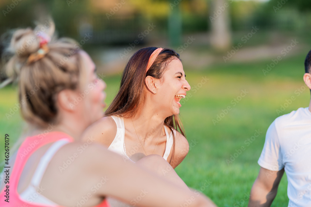 Fototapeta premium Selective focus on a woman laughing while sitting on a park with some friends