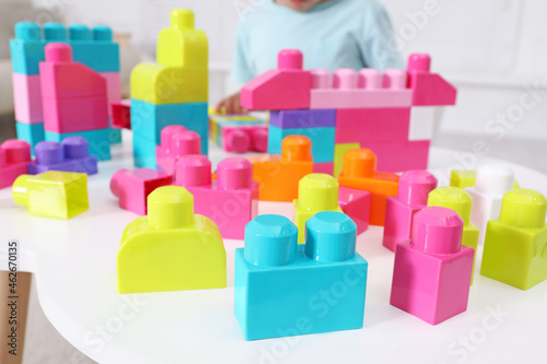 Little child playing with colorful building blocks at table indoors, closeup