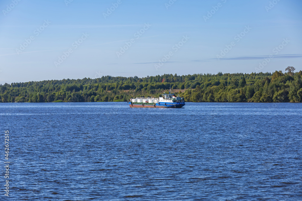 An old oil tanker sails along the Volga river near the forest shore. Yaroslavl Region, Russia