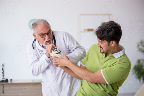 Young male patient visiting old male doctor in expensive medicin