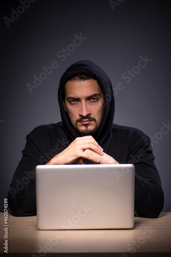 Young male hacker on grey background