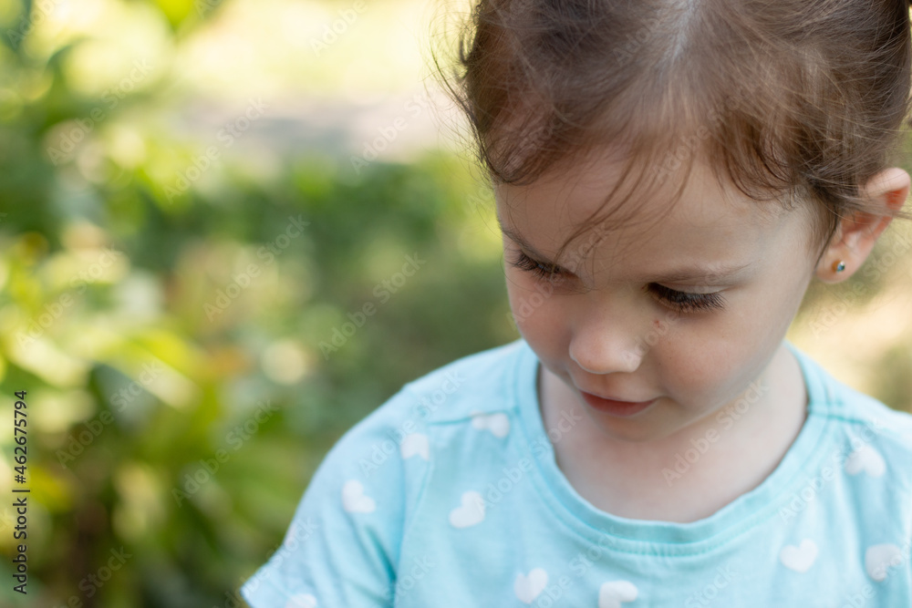 Portrait of a beautiful young girl in a blue t-shirt on a blurred green natural background. Outdoor photo Portrait of a beautiful young girl in a blue t-shirt on a blurred green natural background. Outdoor photo