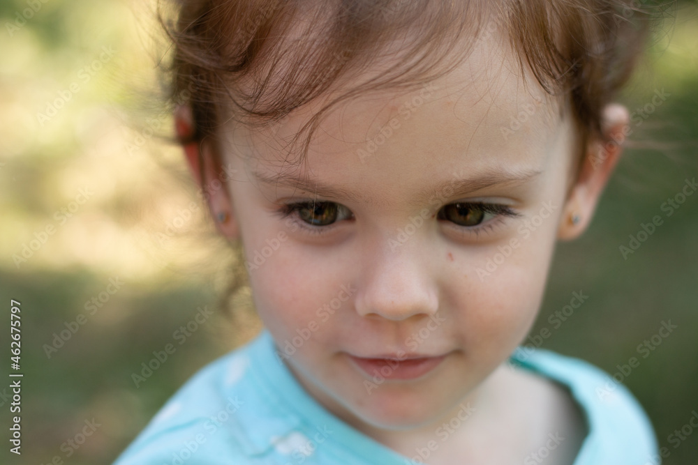 Portrait of a beautiful young girl in a blue t-shirt on a blurred green natural background. Outdoor photo Portrait of a beautiful young girl in a blue t-shirt on a blurred green natural background. Outdoor photo
